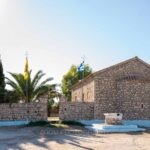 Το πέτρινο εκκλησάκι της Παναγίας Φοινικιάς με κυπαρίσσια και φοίνικα, στις Αλυκές Μεσολογγίου