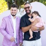 Ο μπαμπάς και ο νονός γελάνε, με τη μικρή να κοιμάται στην αγκαλιά του νονού