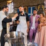 Η μικρή με το λευκό βαπτιστικό χαμογελά σε μια κυρία με ροζ φόρεμα, στο ηλιοβασίλεμα πάνω από τη λιμνοθάλασσα