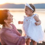 Ο νονός κρατάει τη μικρή τυλιγμένη στο λευκό σεντόνι μετά την κολυμβήθρα, ενώ ο ιερέας θυμιατίζει