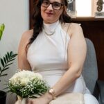 Η Βιβή καθισμένη με λευκό φόρεμα και μπουκέτο από λευκά τριαντάφυλλα, πριν από τον πολιτικό της γάμο στο Αγρίνιο