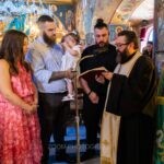 Ο ιερέας διαβάζει τις ευχές της βάπτισης μπροστά στην οικογένεια της Αλίνας