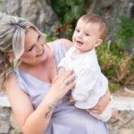 Η νονά κρατά τον Γεράσιμο δίπλα στον βράχο της εκκλησίας και γελούν