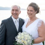 Η Θωμαή και ο Δημήτρης χαμογελούν στο κάγκελο με θέα τη λίμνη