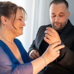Κυρία με μπλε φόρεμα βάζει τα μανικετόκουμπα στον γαμπρό