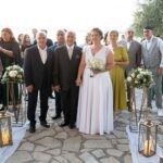 Το ζευγάρι με τους καλεσμένους στο προαύλιο, ανάμεσα σε φανάρια και λευκά λουλούδια