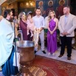 Γονείς και νονοί γύρω από τη χάλκινη κολυμβήθρα με τις αναμμένες λαμπάδες