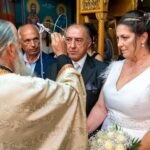Ο ιερέας κρατά τα στέφανα πάνω από τη Θωμαή και τον Δημήτρη