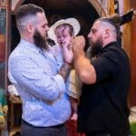 Ο Νίκος κρατά την Αλίνα με το καπελάκι της και ο νονός στέκεται δίπλα
