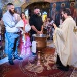 Ο ιερέας μπροστά στην κολυμβήθρα με την οικογένεια της Αλίνας
