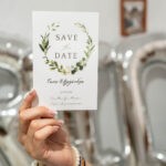 Χέρι κρατά την κάρτα Save the Date του Τάσου και της Αλεξάνδρας