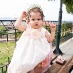 Η Αλίνα με το βαπτιστικό της φόρεμα και το στεφανάκι, με θέα το Αγρίνιο