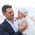 Ο νονός κρατά τη Μαριάνθη στην αγκαλιά του με φόντο την πόλη του Αγρινίου