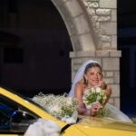 Η Αλεξάνδρα ακουμπά στο κίτρινο ταξί του Τάσου, στολισμένο με λευκά λουλούδια